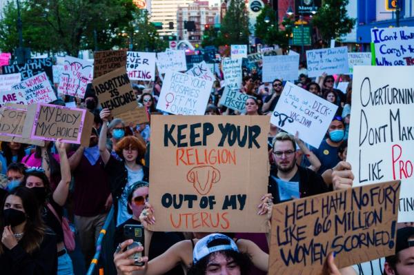 Protesters march with placards expressing their opinion after sunset during Scotus protest.